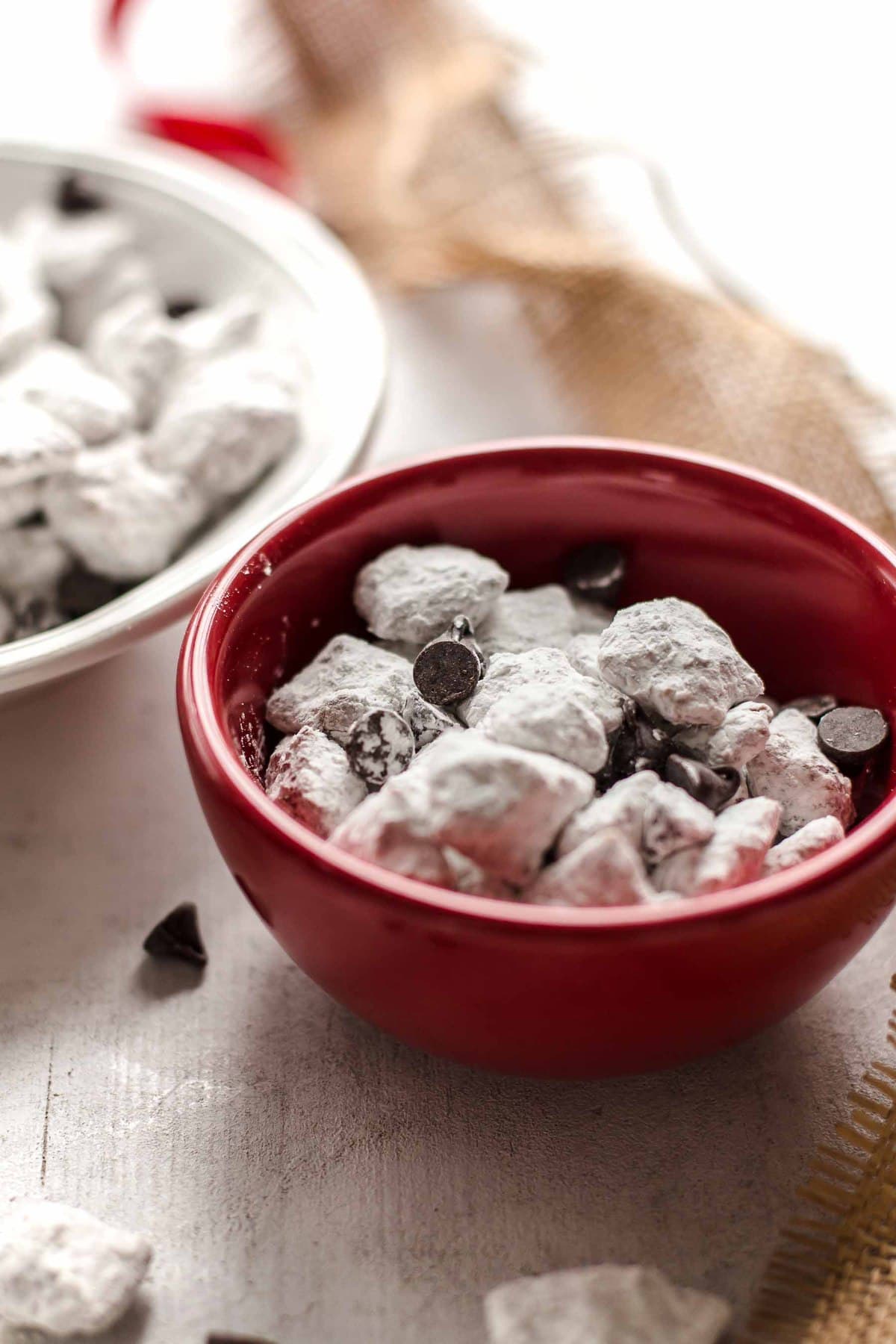 small red bowl of caramel puppy chow with chocolate chips