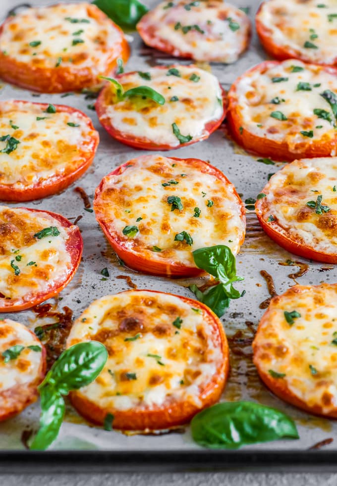 angled shot of baked tomatoes with cheese and basil