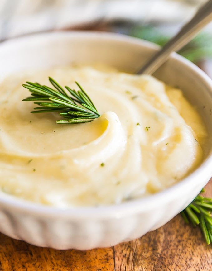 Garlic Mashed Cauliflower Recipe with Rosemary may be healthier, but tastes just as good as Mashed Potatoes! This Mashed Cauliflower is perfect for Thanksgiving, Christmas, Easter, or any day of the year. You won't regret making this Garlic Mashed Cauliflower Recipe; missing out on calories and gaining all the flavor! This healthy side dish will be your new favorite recipe.