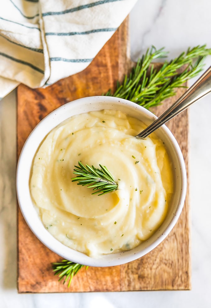 Garlic Mashed Cauliflower Recipe with Rosemary may be healthier, but tastes just as good as Mashed Potatoes! This Mashed Cauliflower is perfect for Thanksgiving, Christmas, Easter, or any day of the year. You won't regret making this Garlic Mashed Cauliflower Recipe; missing out on calories and gaining all the flavor! This healthy side dish will be your new favorite recipe.