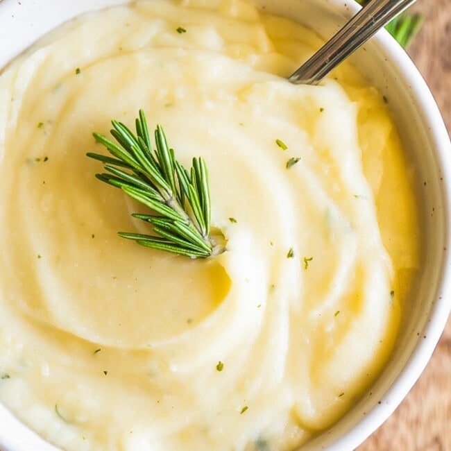 Garlic Mashed Cauliflower Recipe with Rosemary may be healthier, but tastes just as good as Mashed Potatoes! This Mashed Cauliflower is perfect for Thanksgiving, Christmas, Easter, or any day of the year. You won't regret making this Garlic Mashed Cauliflower Recipe; missing out on calories and gaining all the flavor! This healthy side dish will be your new favorite recipe.