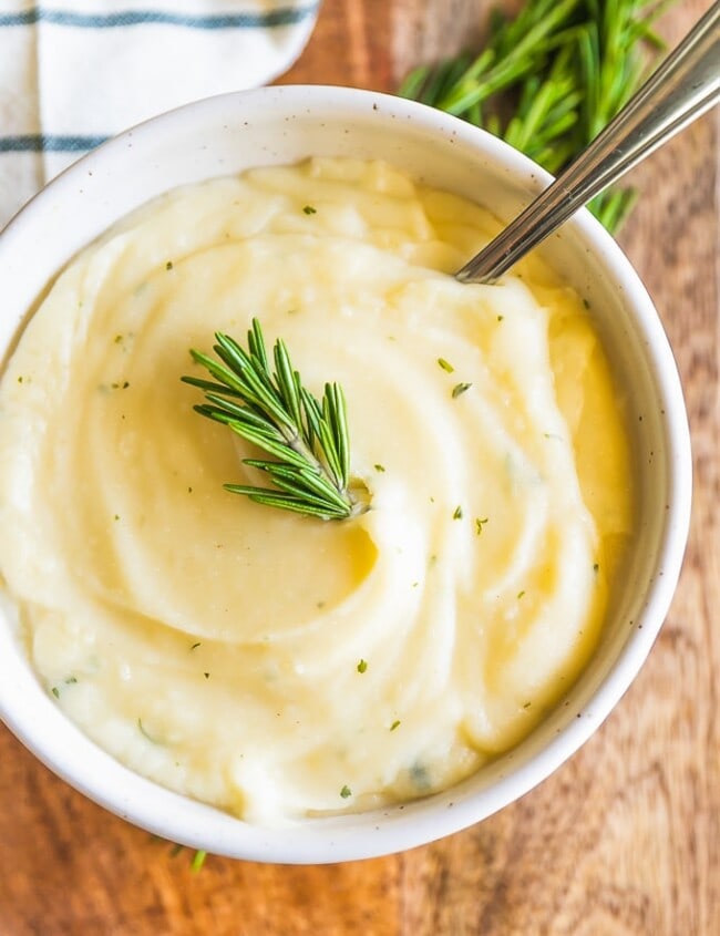 Garlic Mashed Cauliflower Recipe with Rosemary may be healthier, but tastes just as good as Mashed Potatoes! This Mashed Cauliflower is perfect for Thanksgiving, Christmas, Easter, or any day of the year. You won't regret making this Garlic Mashed Cauliflower Recipe; missing out on calories and gaining all the flavor! This healthy side dish will be your new favorite recipe.