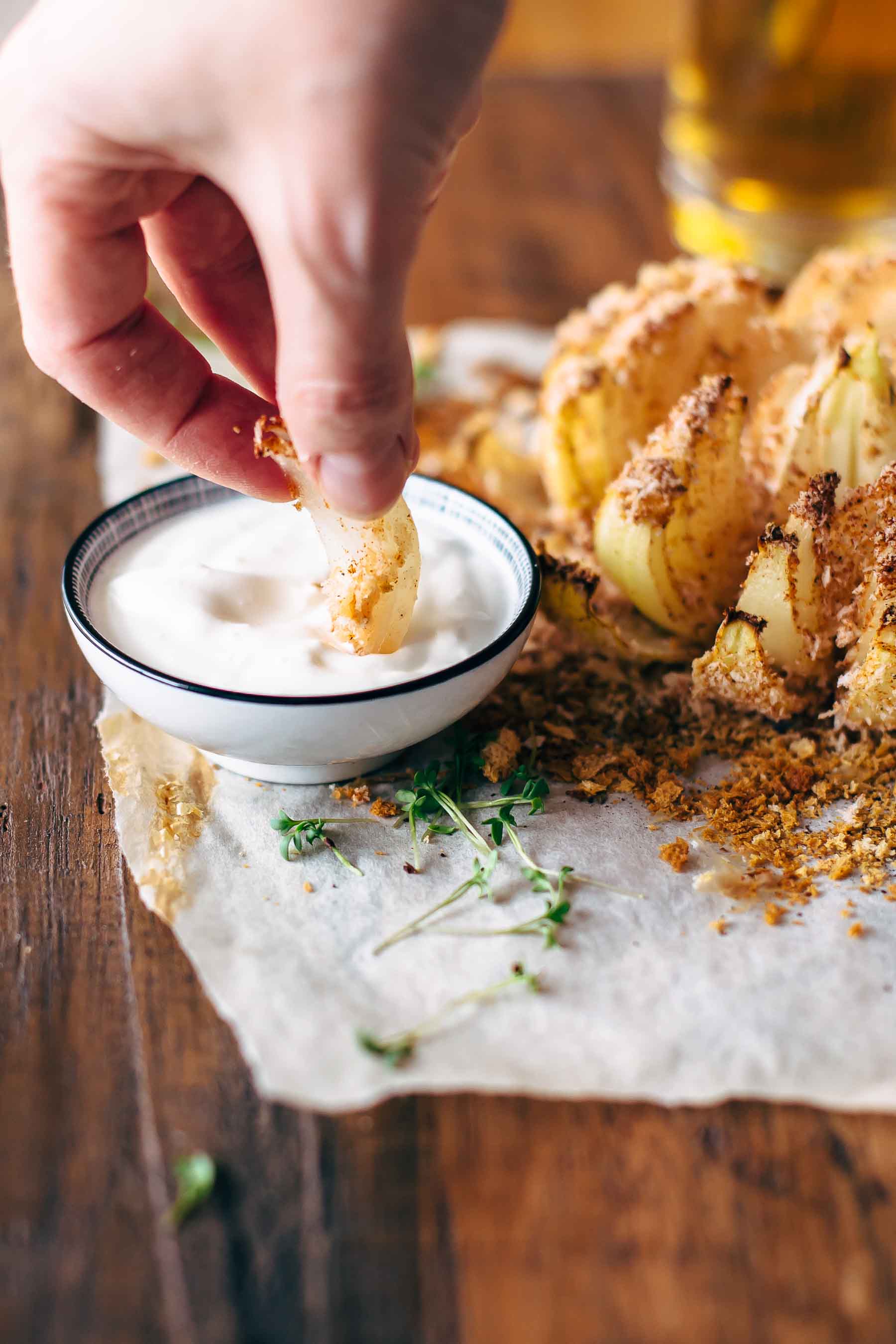 dipping a piece of baked bloomin onion appetizer recipe in ranch