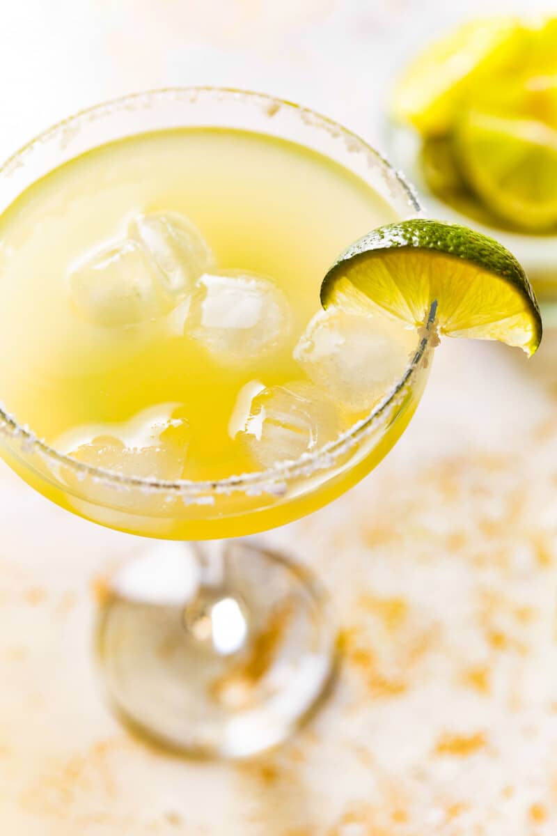 overhead view of a beer margarita in a coupe glass with a salt rim and a lime wedge.