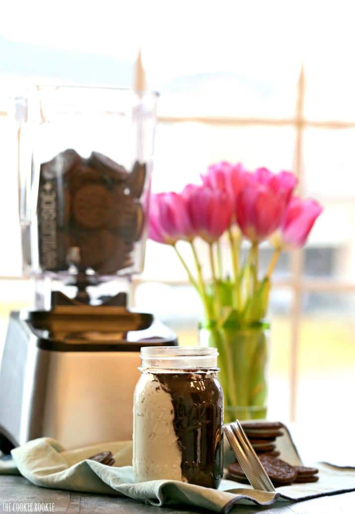 a jar of cookie butter in front of blender of oreos 
