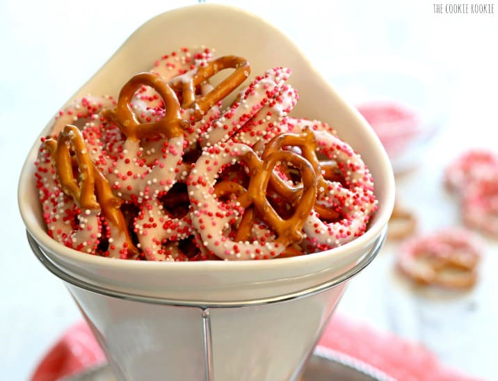 pink yogurt covered pretzels with pink sprinkles in a white bowl