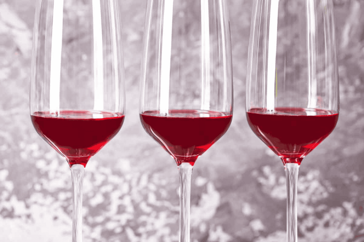 Blackberry syrup in 3 champagne flutes.