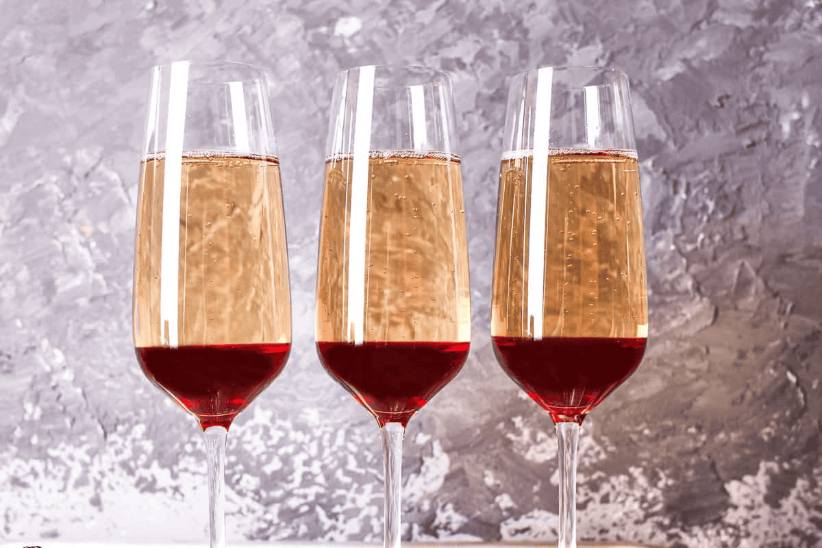3 glasses of champagne layered on top of blackberry syrup.