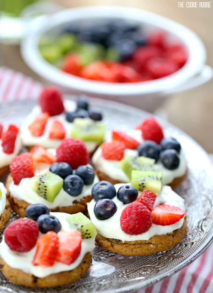 Mini Chocolate Chip Cookie Fruit Pizzas! Such a fun Spring Dessert! Chocolate Chip Cookie base topped with White Chocolate Cream Frosting and mixed fruit!