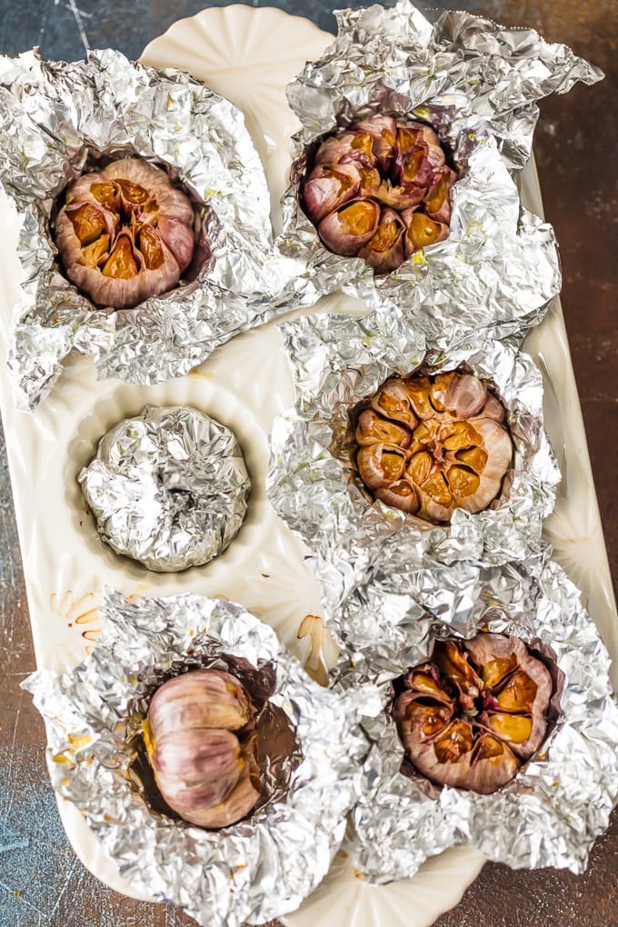 garlic covered in foil in cupcake baking dish