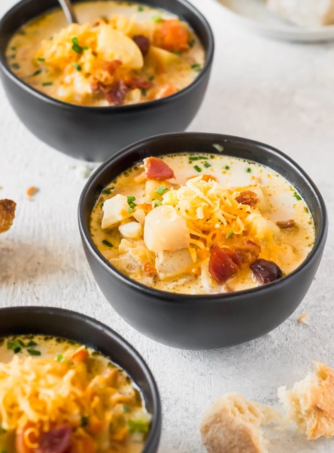 three bowls of crockpot potato soup loaded up with toppings