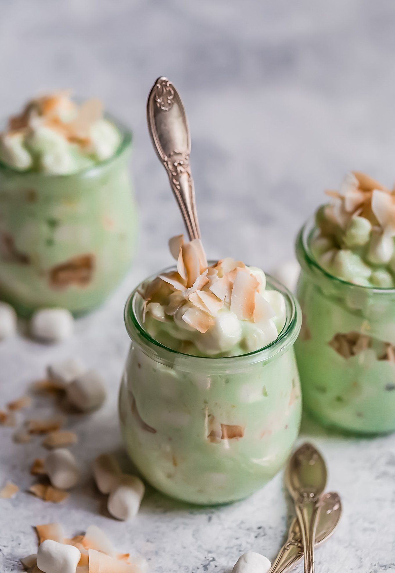 jars of watergate salad topped with marshmallows and toasted coconut