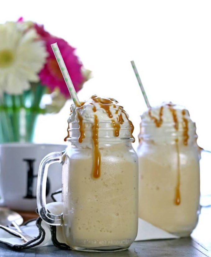 Caramel Frappuccino in front of a vase of daisies