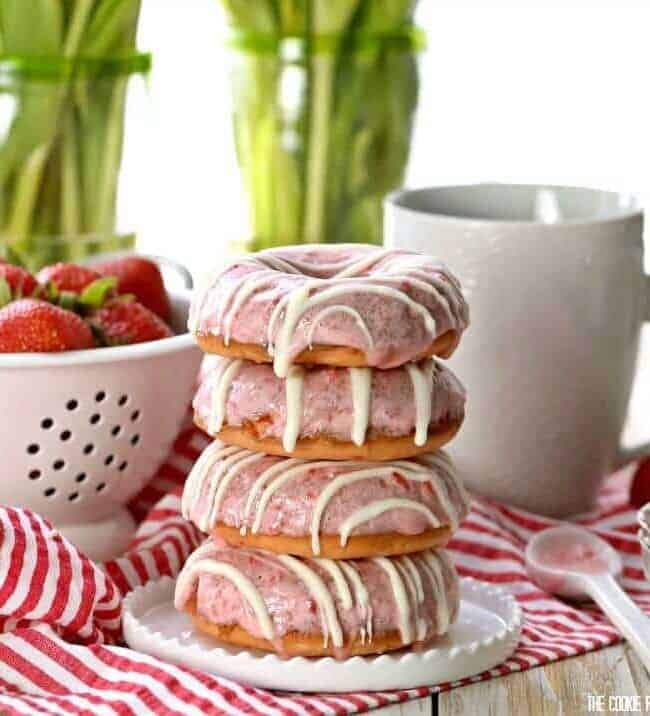 Strawberries and Cream Cake Mix Donuts on a plate in front of a coffee mug and colander of strawberries