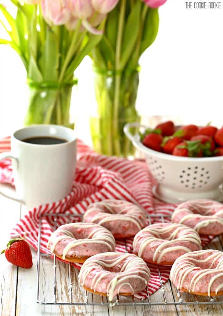 wire rack with donuts, a mug of coffee, and strawberries on a table