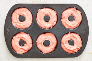 strawberry donut batter in a donut tin.