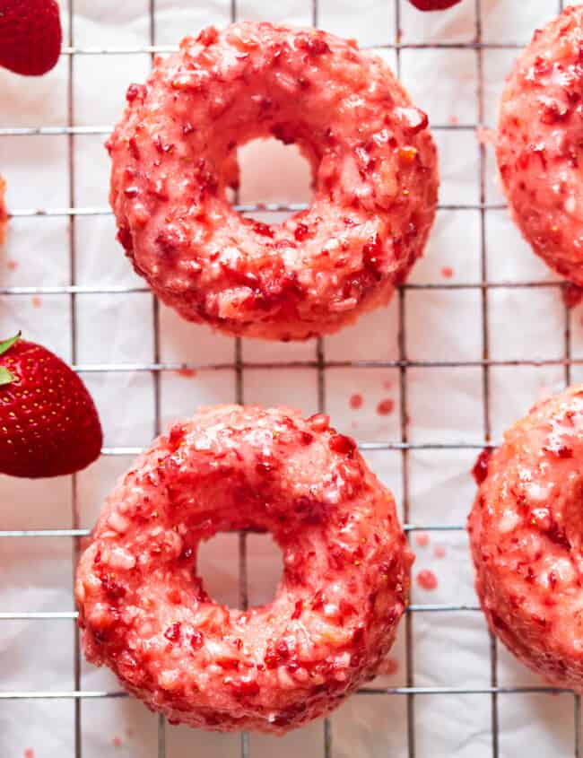 overhead view of strawberry donuts on a wire cooling rack.