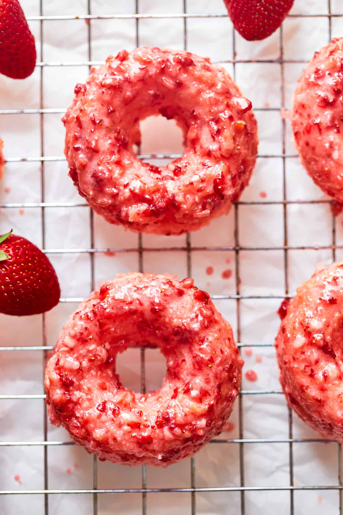 overhead view of strawberry donuts on a wire cooling rack.