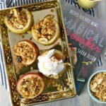 a tray full of apples and granola on a table next to a book.