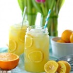 two mason jars filled with lemonade and sliced oranges.