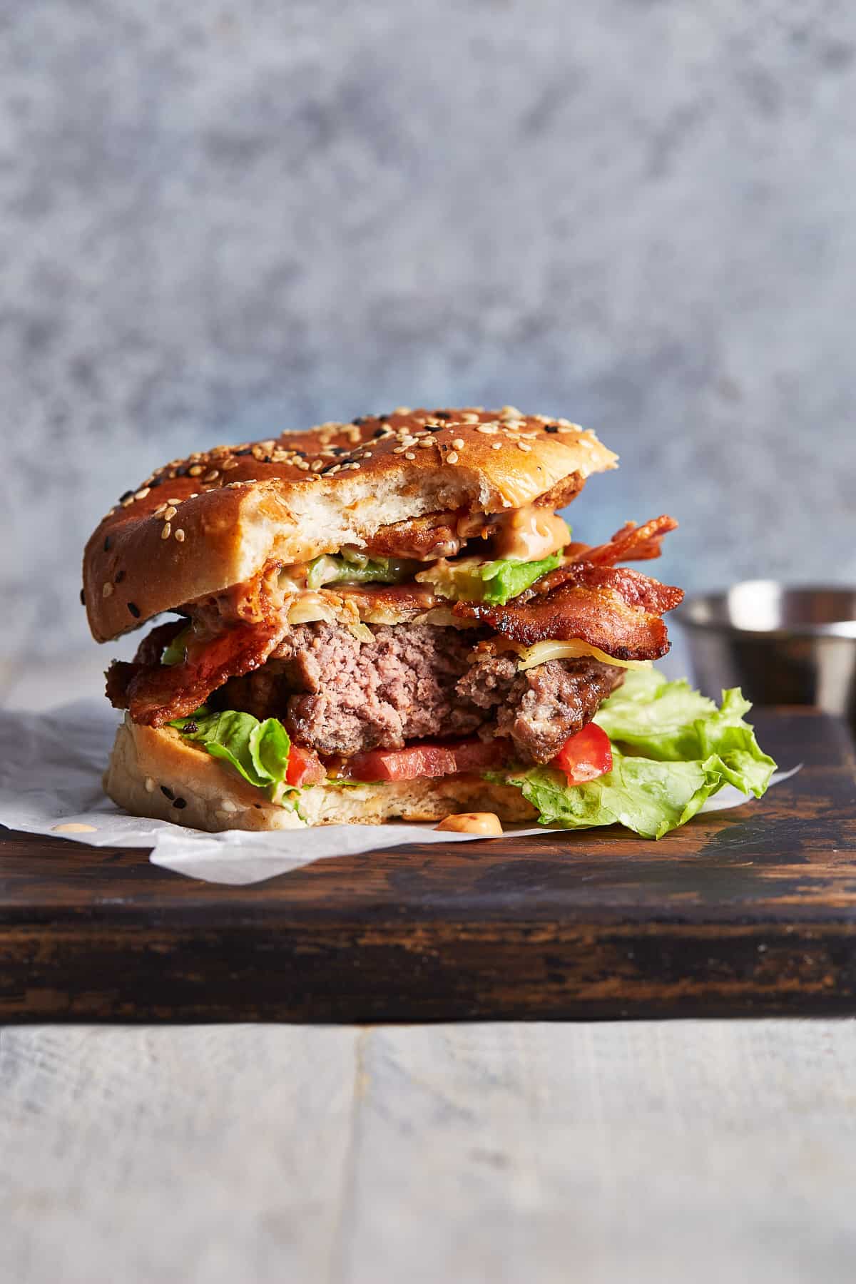 Cowboy Burgers loaded with avocado, onion rings, bacon, and cheese? YUM! It doesn't get better than this Loaded BBQ Burger recipe with Spicy Mayo. BBQ dreams do come true! Cowboy burger with a bite taken out of it.