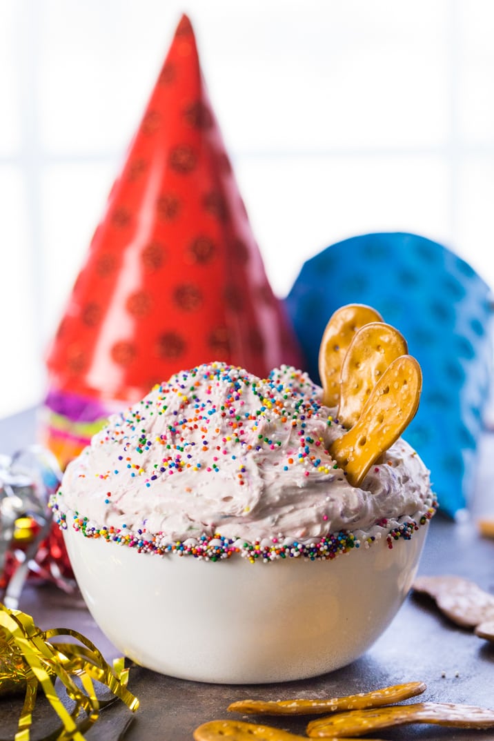 cake batter dip topped with sprinkles in front of party hats