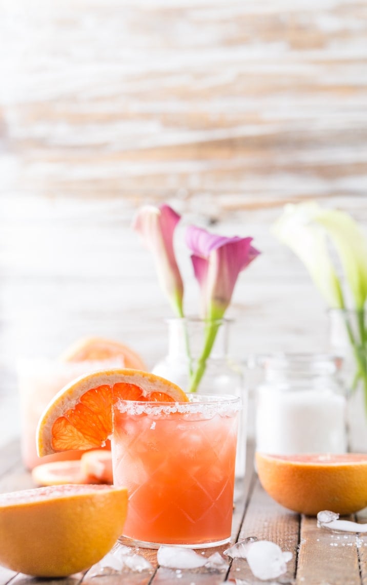 cocktail on table with grapefruits and flowers