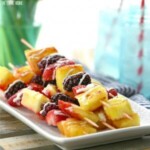 a plate of fruit skewers on a white plate.