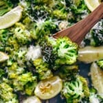 broccoli on a baking dish with lemon wedges and parmesan