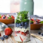 mason jar salad on a table surrounded by berries