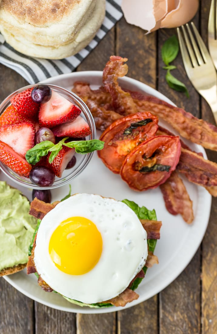 breakfast with berries, bacon, sandwich, and grilled veggies on a plate
