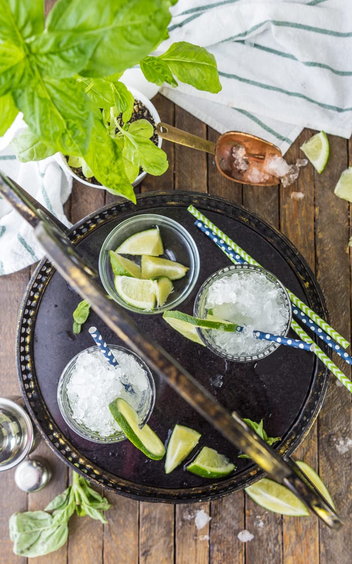 top view of mojitos with straws, lime wedges, and crushed ice