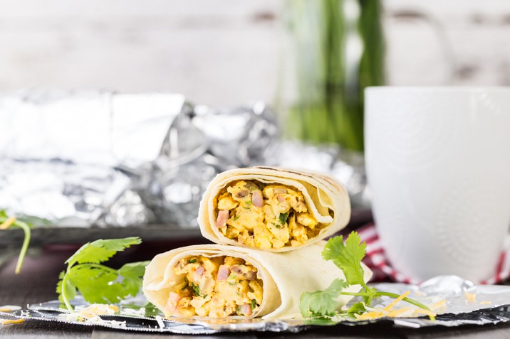 breakfast burritos stacked in front of a coffee mug