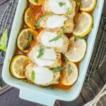 a baking dish with chicken breasts and lemon slices.