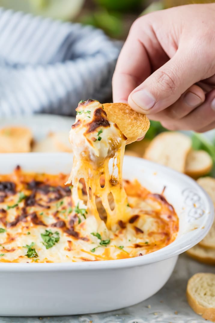dipping toasted bread into a bowl of cheese dip