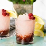 two glasses with raspberry ice cream and lemon wedges.