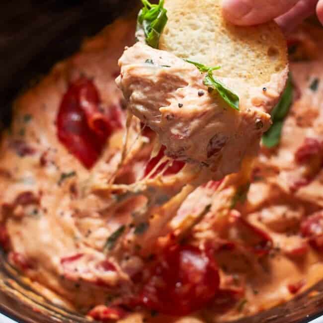 dipping toasted bread in crockpot pizza dip