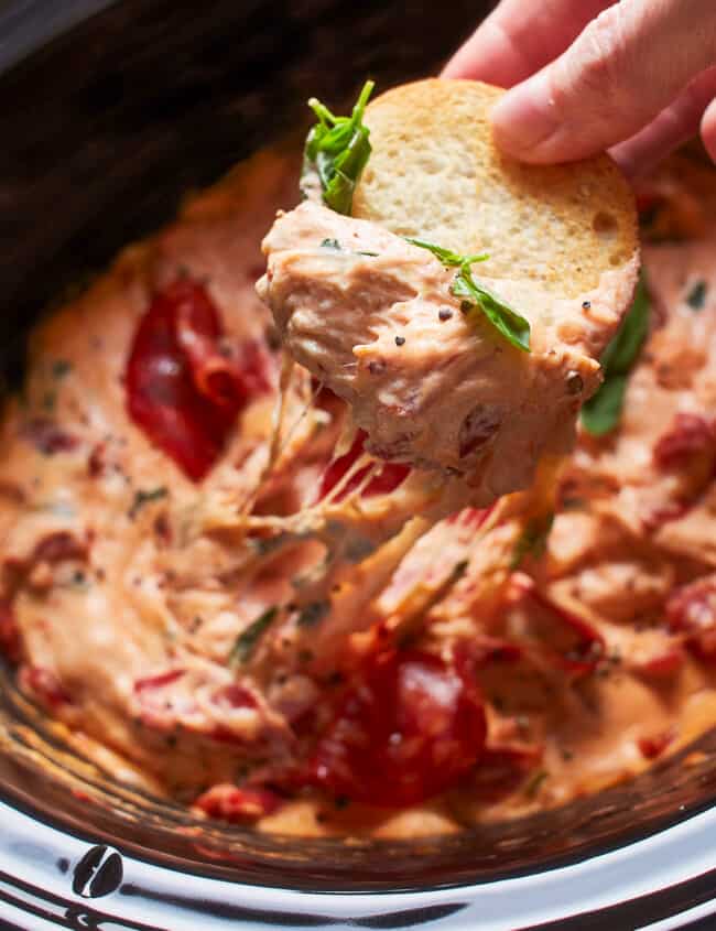dipping toasted bread in crockpot pizza dip
