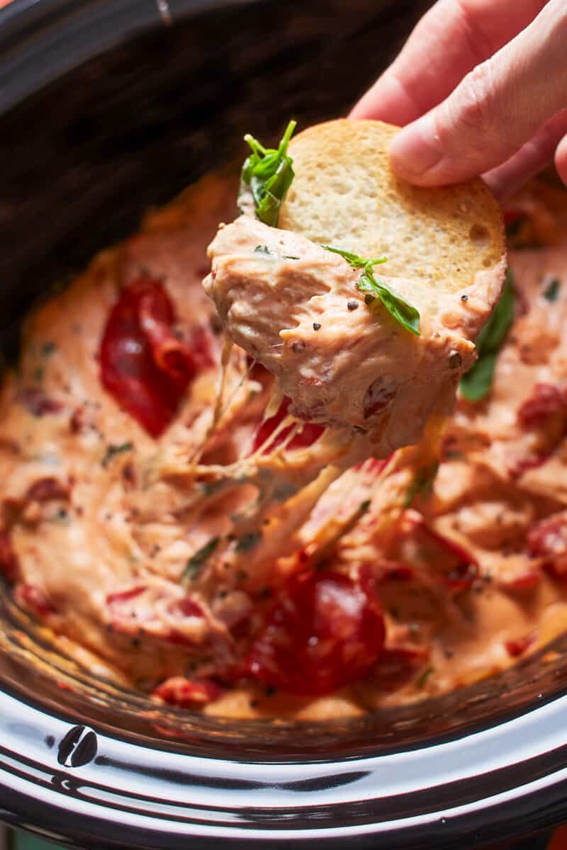 dipping toasted bread in crockpot pizza dip