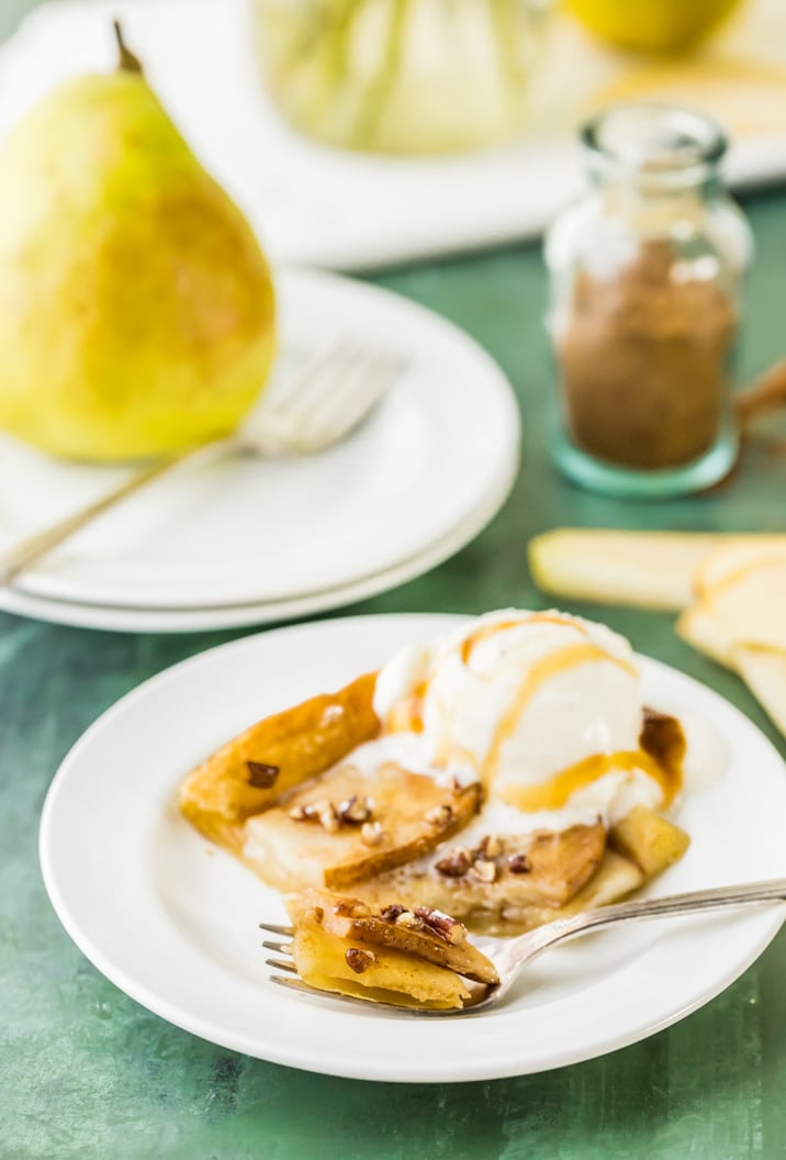 slice of pears tart on a plate with a scoop of ice cream.