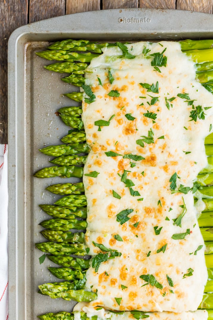 Asparagus covered in cheese, on a baking tray
