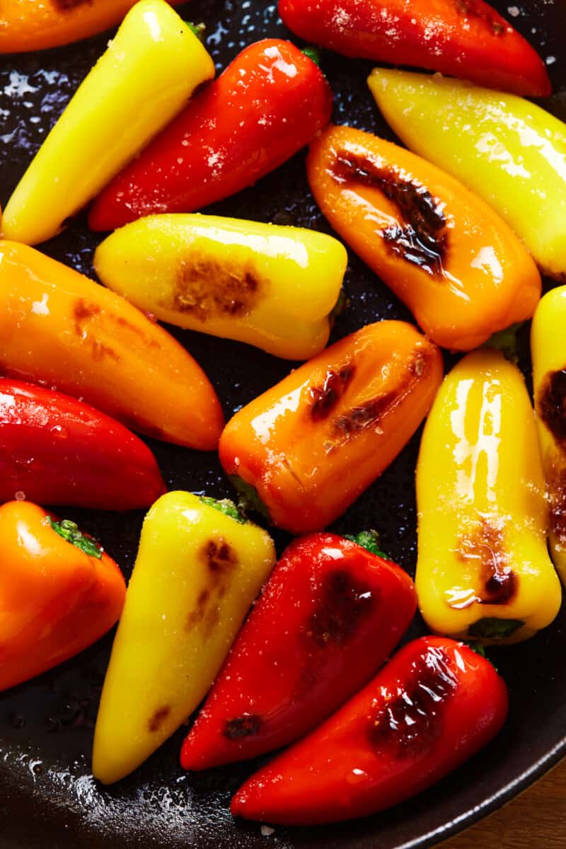 overhead view of tricolor blistered sweet peppers in a black bowl.