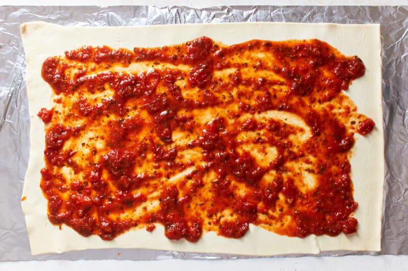 sauce spread over rolled out pizza roll dough.