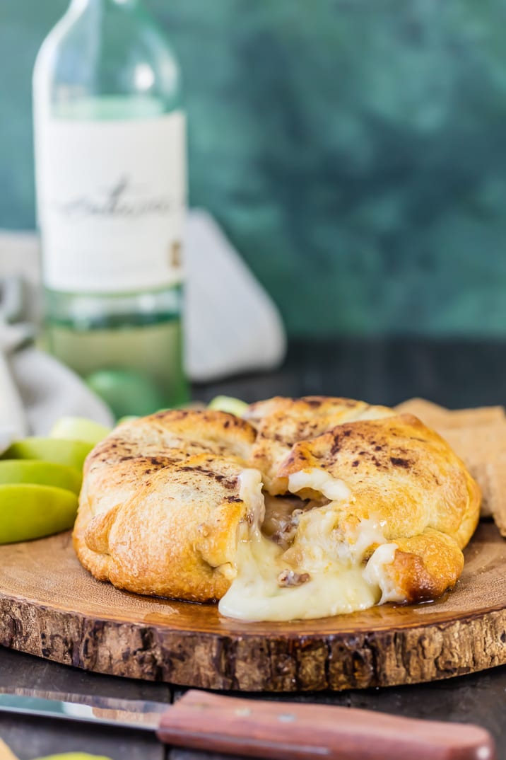 apple pie baked brie on wooden board with wine in background