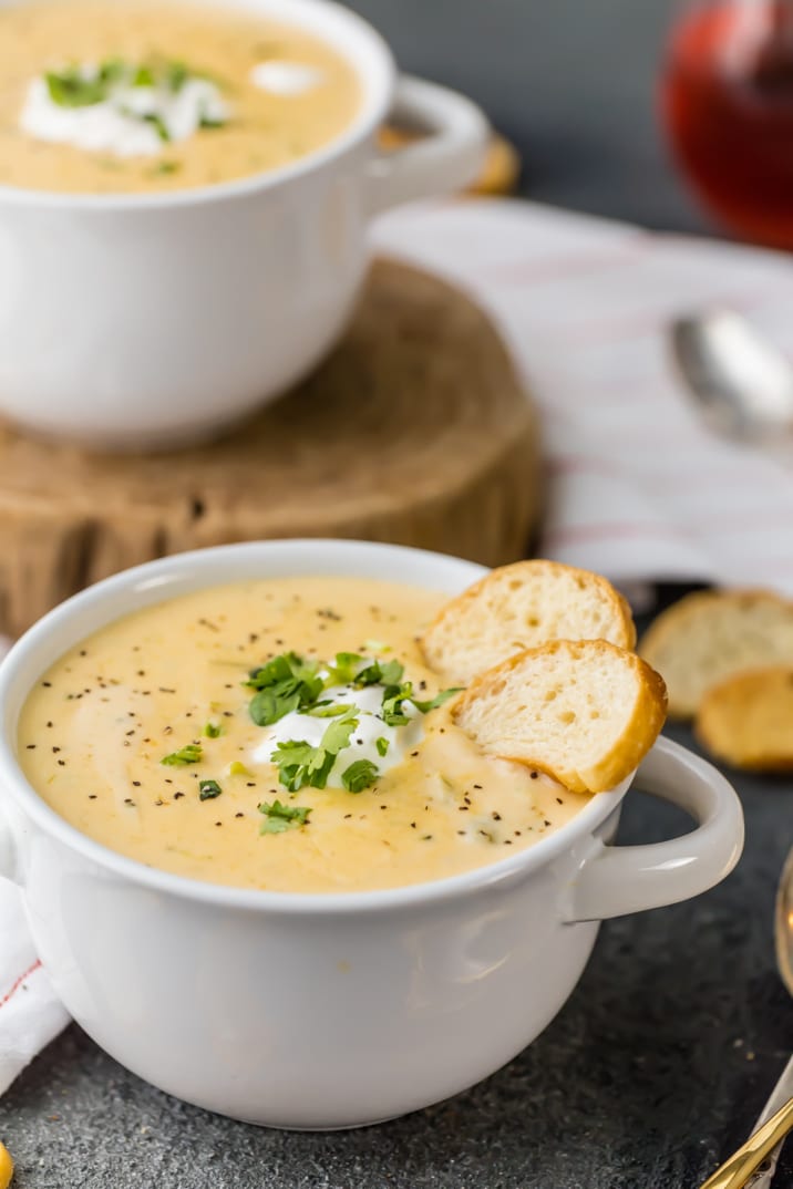 A bowl of slow cooker broccoli cheese soup with two slices of bread dipped in