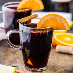 glasses of mulled wine topped with oranges and cinnamon sticks