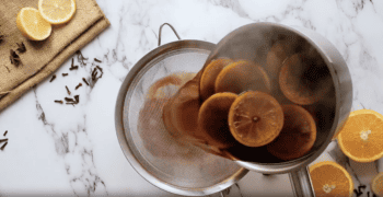A pan with mulled wine and orange slices simmering with spices.