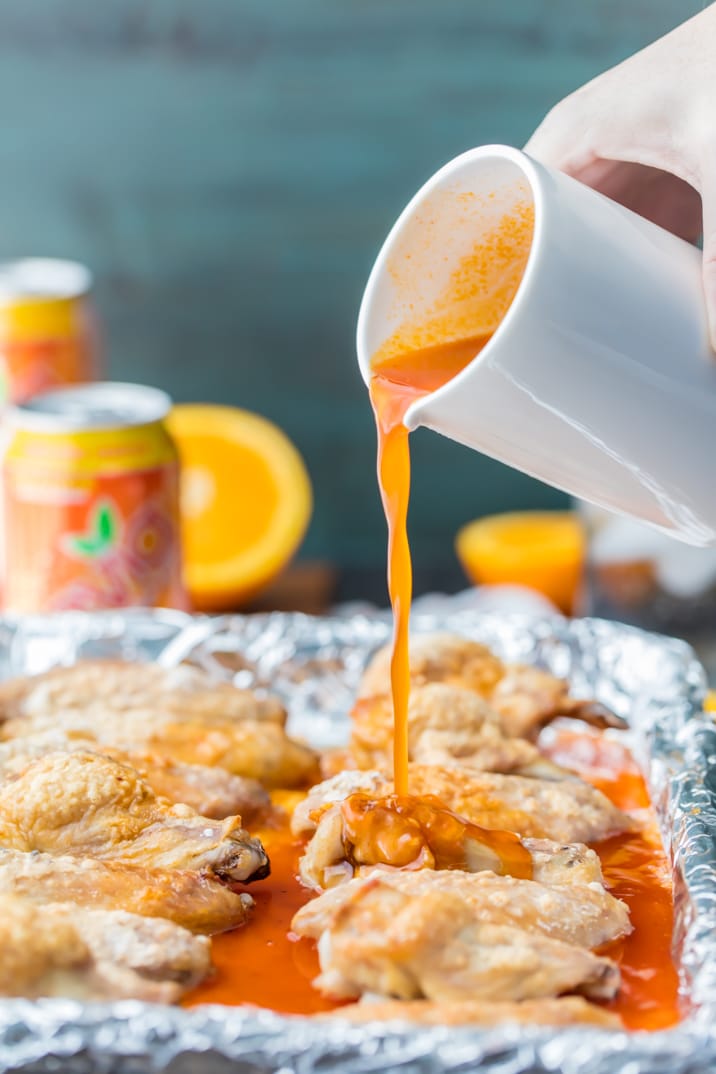 pouring orange soda hot wing sauce over baked hot wings