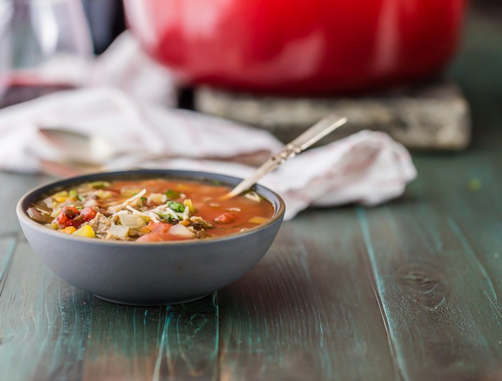 A bowl of soup, with a red pot in the background