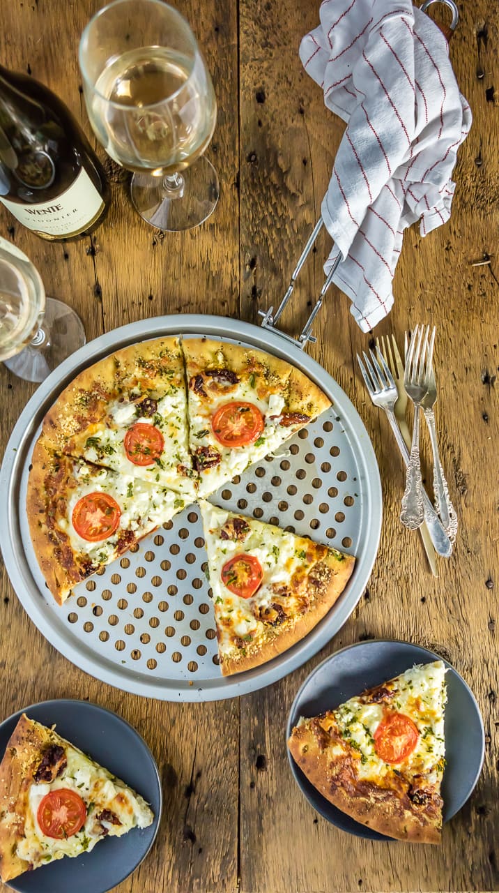 easy gourmet white pizza on tray and slices on plates, with forks and wine glasses